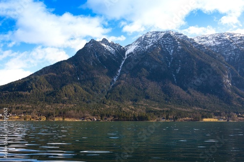 View idyllic Alpine mountains, lake Hallstattersee and small houses in valley. Sunny morning in Austria