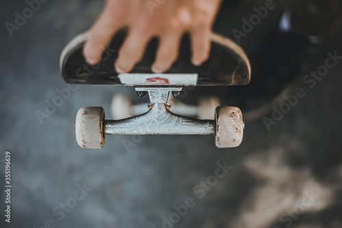 Guy holds a skateboard on the street.