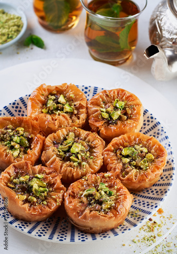 Middle eastern arab sweet pastry baklava with honey, pistachios, mint tea on a light background. Selective focus. Ramadan, Eid concept.
