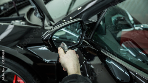 Detailer applying a layer of paint protection film on a sports car © camerarules