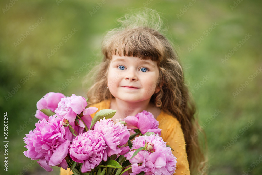Little girl is playing in the park. The child is walking. Summer rest. Long haired blonde smiles.Beautiful baby with peonies. Girl with a bouquet of flowers Little girl is playing in the park. The child is walking. Summer rest. Long haired blonde smiles.Beautiful baby with peonies. Girl with a bouquet of flowers
