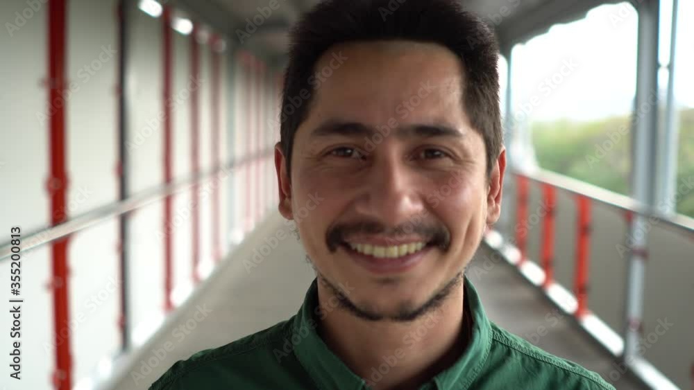 Young man asian smiling and looking at camera. Portrait of a happy handsome young man on skywalk in urban. Close up face of young cool trendy man looking at camera Young man asian smiling and looking at camera. Portrait of a happy handsome young man on skywalk in urban. Close up face of young cool trendy man looking at camera