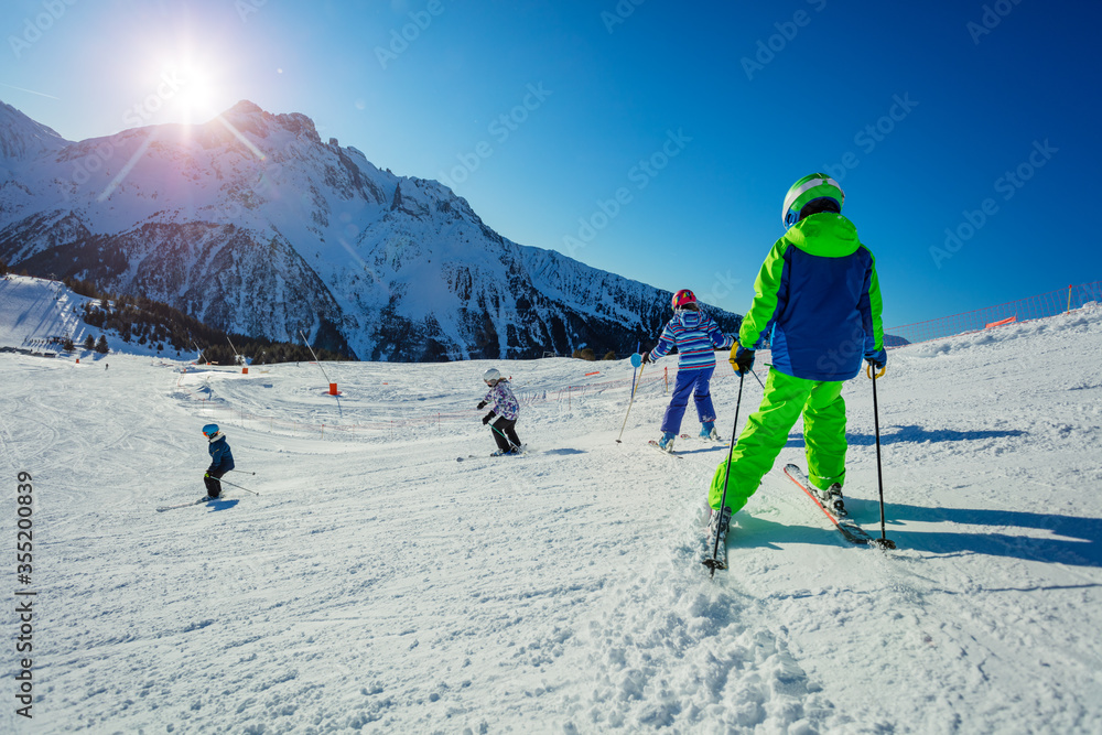 Group of children ski on the hill with friends portrait, sunny day on Alpine mountain resort