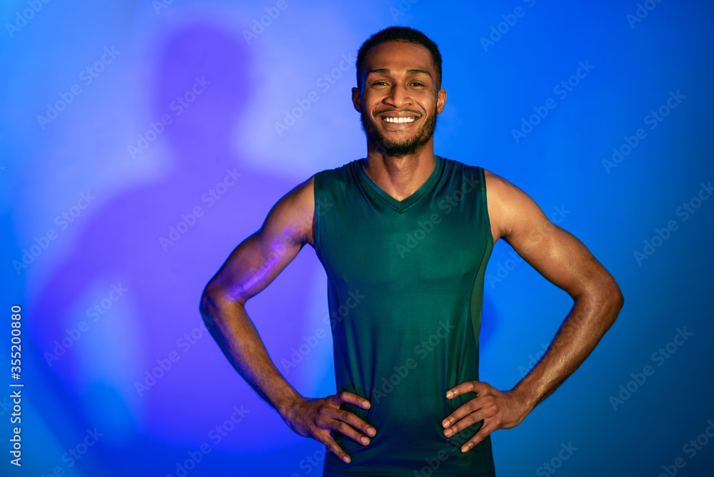 Cheerful Athlete Guy In Fitwear Posing Over Blue Studio Background Cheerful Athlete Guy In Fitwear Posing Over Blue Studio Background