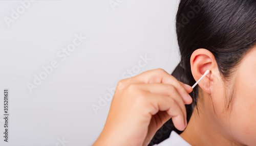 Asian beautiful woman cleaning ear hrt using cotton swab on white background with copy spece for text, healthcare concept