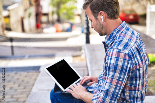 portrait of a trendy young man in the city using tablet