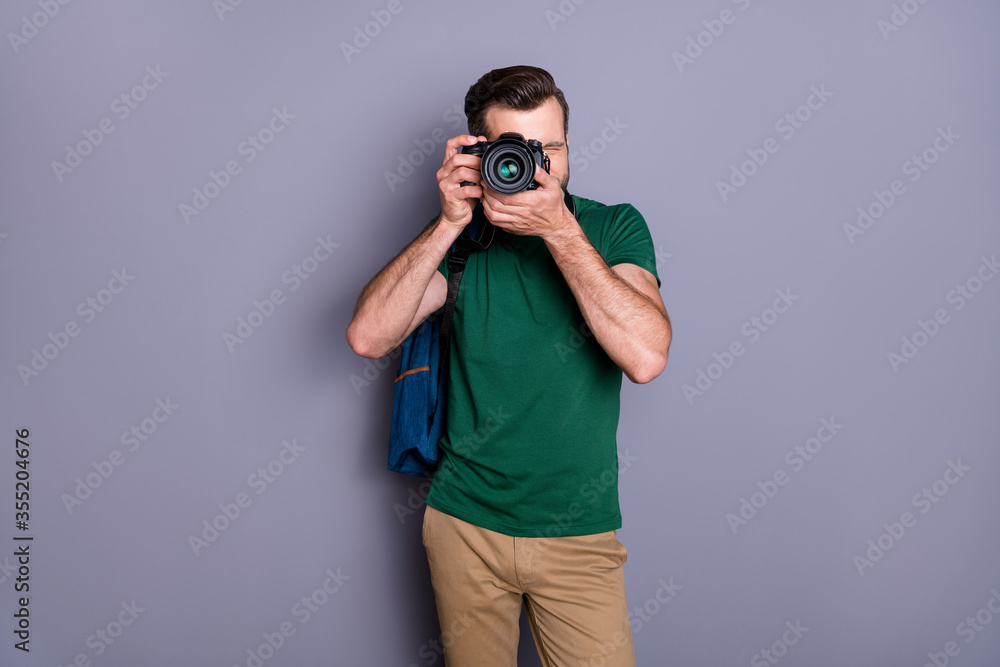 Portrait of concentrated guy enjoy travel weekend use professional camera shooting picture wear green pants isolated over gray color background Portrait of concentrated guy enjoy travel weekend use professional camera shooting picture wear green pants isolated over gray color background