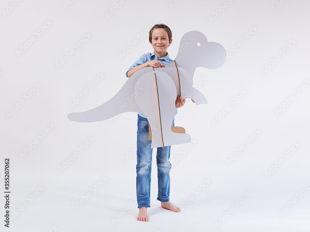 Little dreamer boy playing with a cardboard dinosaur Tyrannosaurus rex. Childhood. Fantasy, imagination. Little dreamer boy playing with a cardboard dinosaur Tyrannosaurus rex. Childhood. Fantasy, imagination.