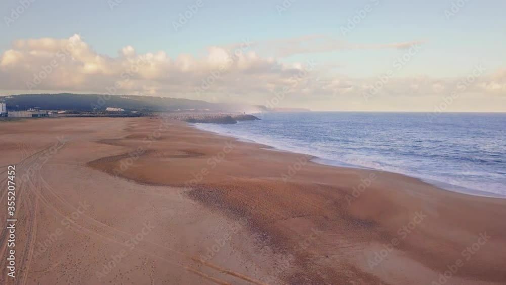 Flying over a sandy beach. Waves break on a sandy beach on the Atlantic coast, aerial View. Nazare, Portugal. Flying over a sandy beach. Waves break on a sandy beach on the Atlantic coast, aerial View. Nazare, Portugal.