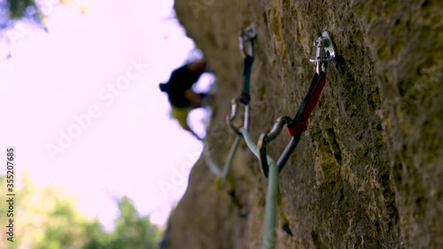 Close-up of rock climbing equipment swinging from rock wall in slow motion