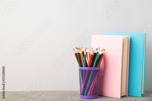 Multi coloured school books and pencils on grey background