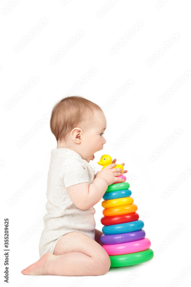 Obraz premium Cute baby playing with colorful rainbow pyramid isolated on a white background. Child with educational toy.
