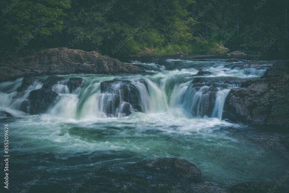 Obraz premium Beautiful flowing waterfall through lush forest in Washington State, Pacific Northwest, United States