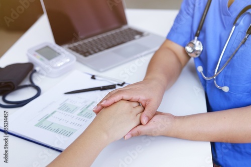 Doctor holding patient's hand, and reassuring woman patient helping hand concept.