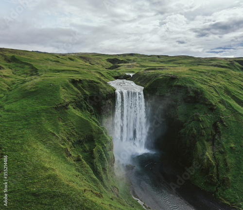 Iceland waterfall Skogafoss in Icelandic nature landscape. Famous tourist attractions and landmarks destination in Icelandic nature landscape on South Iceland. Aerial drone view of top waterfall.