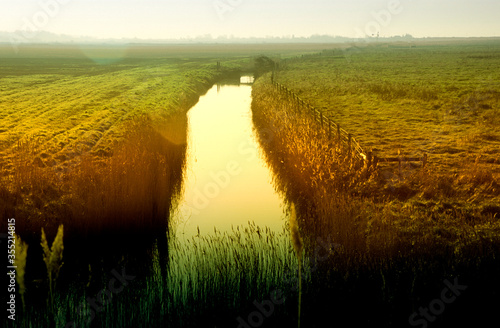 Canvas Print Evening sunset on fen marshland and water in land drain dyke