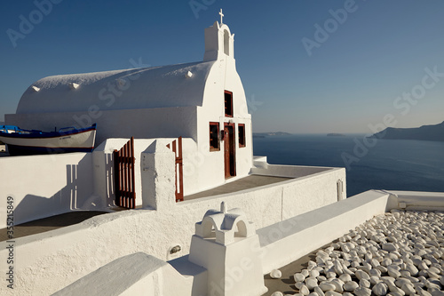 White orthodox church with a traditional boat beside over Santorini caldera