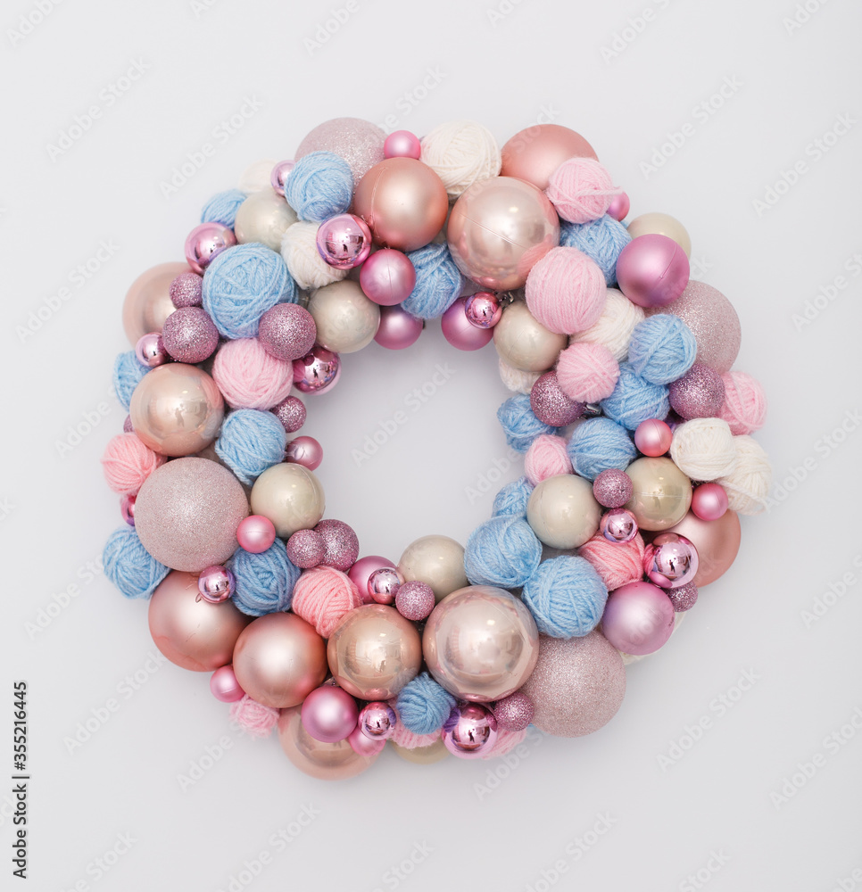 wreath of Christmas balls and clews on white wall. New year decoration in tender pink and blue colors wreath of Christmas balls and clews on white wall. New year decoration in tender pink and blue colors