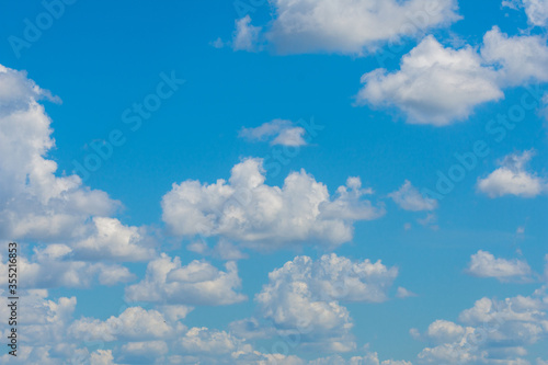 various shape fluffy cummulus clouds accumulating on blue summer sky