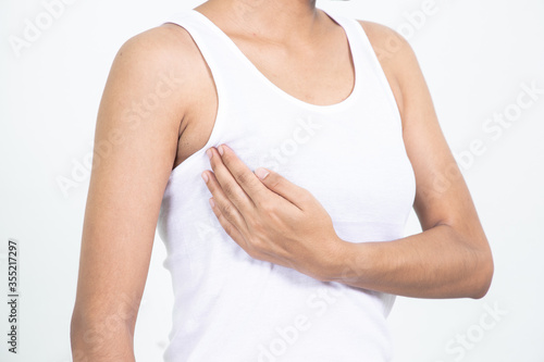 Woman hand checking lumps on her breast for signs of breast cancer on gray background. Healthcare concept. © Teerapong