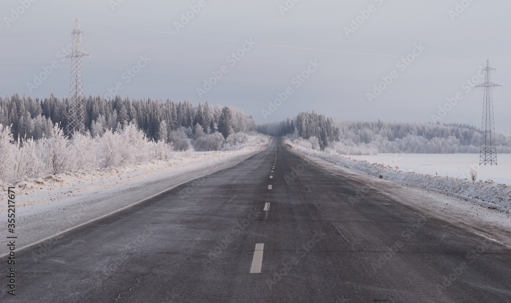 Empty highway and snow-covered forest on a cold December morning. Khanty-Mansiysk. Western Siberia. Russia.