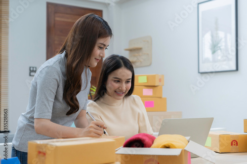 Young Asian woman couples check order together on their laptop at home. Happy Asian businesswoman smiling while working online selling success. 