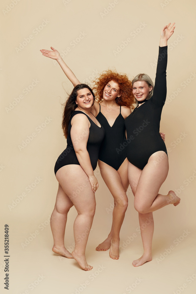 Different Body Types. Group Of Diversity Models Full-length Portrait.  Blonde, Brunette And Redhead In Black Bodysuits Posing On Beige Background.  Female Friendship For Happy Life. Stock-Foto | Adobe Stock