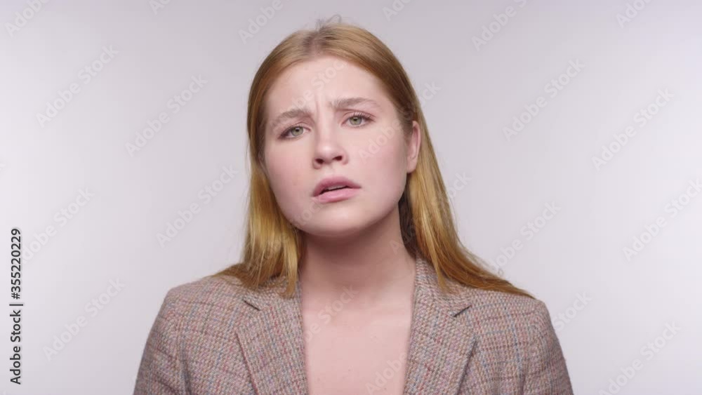Portrait of a young beautiful woman with red blonde hair feels anxious and worried on a studio backdrop Portrait of a young beautiful woman with red blonde hair feels anxious and worried on a studio backdrop