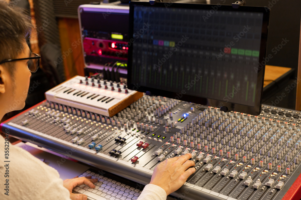 male sound engineer, producer, composer mixing music on audio mixer in recording studio