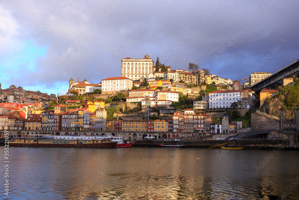 Morning in Porto Portugal: Dark clouds in the sky above Douro river and Ribeira district, featuring sunlit Episcopal palace on the top of the hill.
