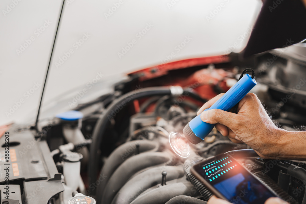 Asian Man mechanic inspection Shine a torch car engine checking bug in engine from application smartphone.Red car for service maintenance insurance with car engine.for transport automobile automotive Asian Man mechanic inspection Shine a torch car engine checking bug in engine from application smartphone.Red car for service maintenance insurance with car engine.for transport automobile automotive