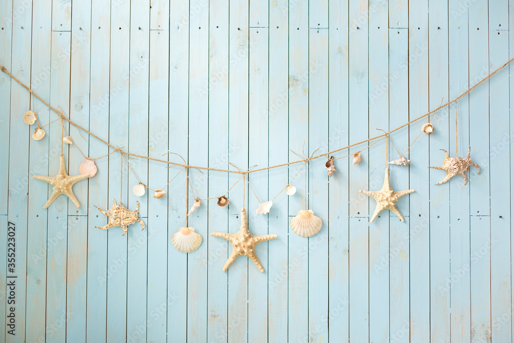 Fototapeta premium Blue wooden wall with a garland from sea shells