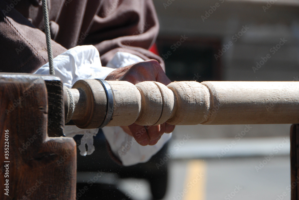 A turner works at one wood leg of a table A turner works at one wood leg of a table