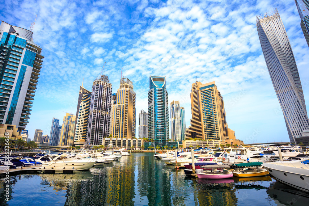 Marina for small boats and yachts in Dubai UAE, surrounded by tall skyscrapers. Luxury vacation tourist destination and real estate investment and development opportunity. Skyline of a modern city.