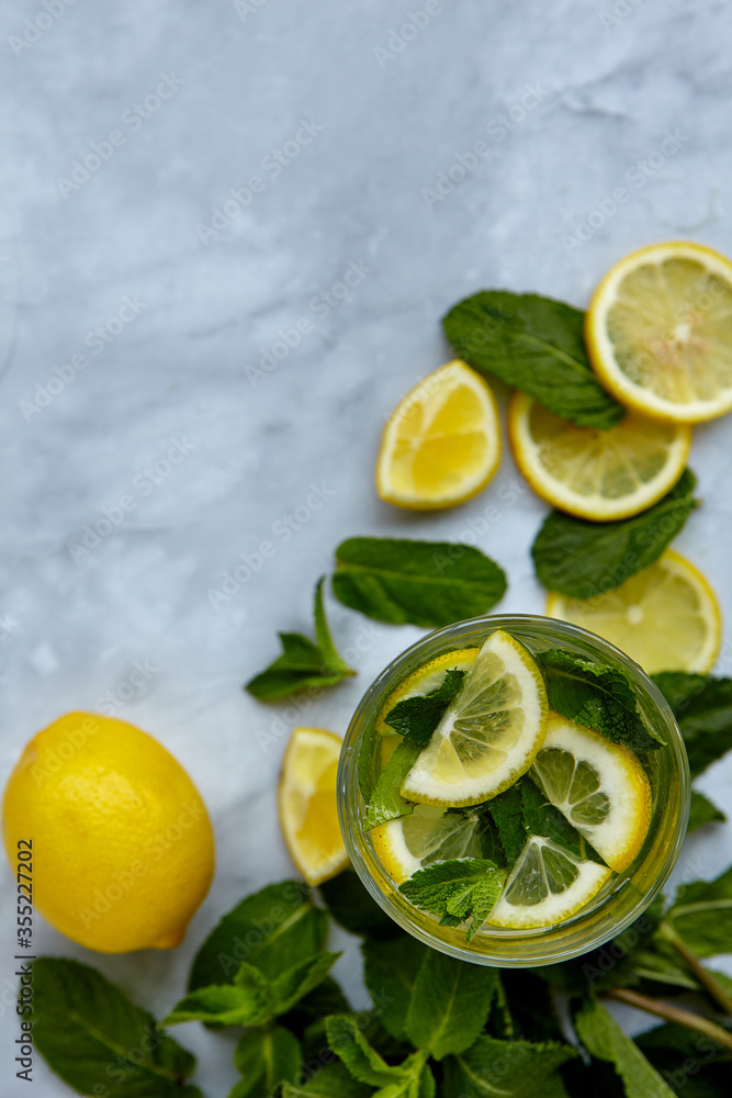 Refreshing drinks for summer, cold sweet and sour lemonade juice in the glasses with sliced fresh lemons. Refreshing summer drink. Traditional lemonade with lemon, mint and ice. Selective focus Refreshing drinks for summer, cold sweet and sour lemonade juice in the glasses with sliced fresh lemons. Refreshing summer drink. Traditional lemonade with lemon, mint and ice. Selective focus