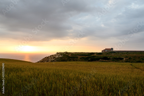 Old church in Portugal on a hill by the ocean at sunset.