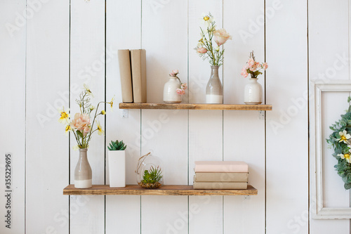 shelf with flowers and books on white wall
