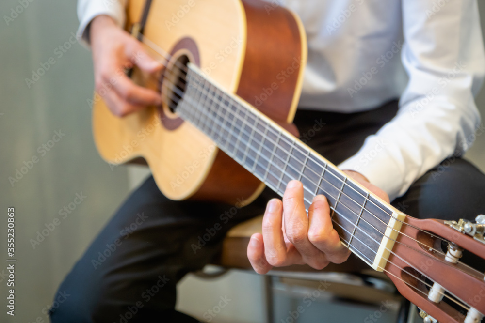 Classical guitar - Guitarist playing acoustic guitar in studio - selective focus close-up of the fingerboard and hand