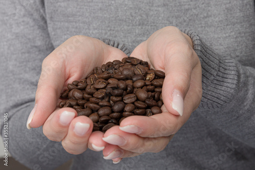 close up of woman's hands holding a lot of coffee beans