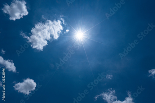 Bright blue sky with clouds and sun ray