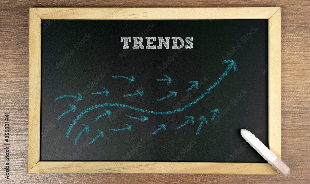 TRENDS word written on a chalkboard with a green arrow, leader concept TRENDS word written on a chalkboard with a green arrow, leader concept
