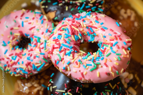  donuts, close-up photo with selective focus - assorted donuts with chocolate frosted, pink glazed and sugary sprinkles. 