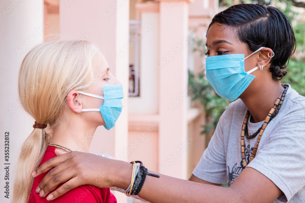 portrait of two Caucasian and African girls in protective medical masks, coronavirus concept. multinational friendship. lockdown is over, the end of the epidemic. quarantine finish. portrait of two Caucasian and African girls in protective medical masks, coronavirus concept. multinational friendship. lockdown is over, the end of the epidemic. quarantine finish.