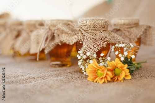 Jars with honey and orange flowers on a sacking background