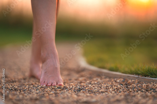 barefoot girl walking on the walkway ground stone with sunset light shine