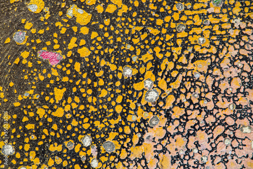 Abstract image of several layers of scaling and peeling paint on the facade of a house, resembling leopard skin background.