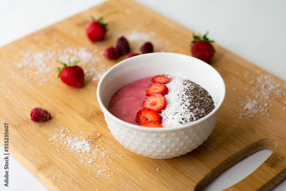 Healthy vegan trendy breakfast: magenta pink berry smoothie bowl made with frozen bananas, raspberry, strawberry and coconut milk. Topped with coconut flakes chia seeds and sliced strawberry. Healthy vegan trendy breakfast: magenta pink berry smoothie bowl made with frozen bananas, raspberry, strawberry and coconut milk. Topped with coconut flakes chia seeds and sliced strawberry.