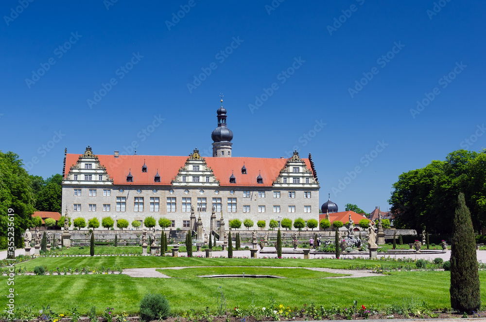 Weikersheim Castle in Germany, view from beautiful baroque garden with flowers, fountains and sandstone figures