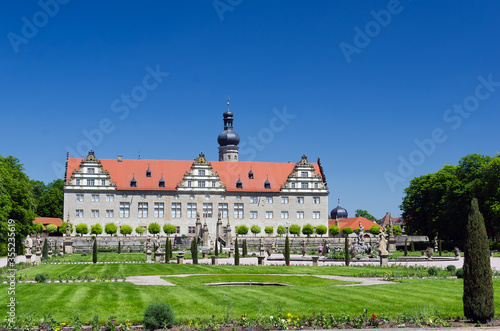 Weikersheim Castle in Germany, view from beautiful baroque garden with flowers, fountains and sandstone figures