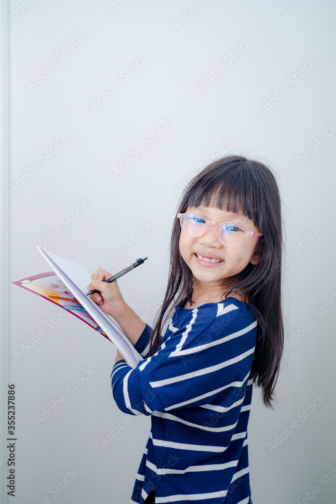 Funny little girl holds a placard plate for inscriptions. Gray background Funny little girl holds a placard plate for inscriptions. Gray background